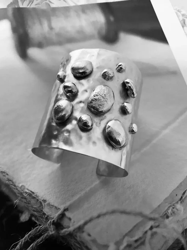 Handmade hammered gold cuff bracelet with organic silver pebble accents, front view